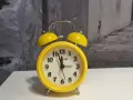 Żółty budzik z dzwonkami, który może oznaczać zakłócanie ciszy nocnej.