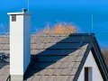 System odgromienia domu na dachu z dachówki, z kominem i piorunochronem.