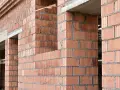 Ściany z pustaków ceramicznych w trakcie budowy. Widoczne różne rodzaje pustaków, tworzące solidną konstrukcję.