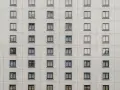 Szare okna w białej, ceglanej elewacji bloku. Wiele identycznych okien, jak w mieszkaniach za odstępne od administracji.