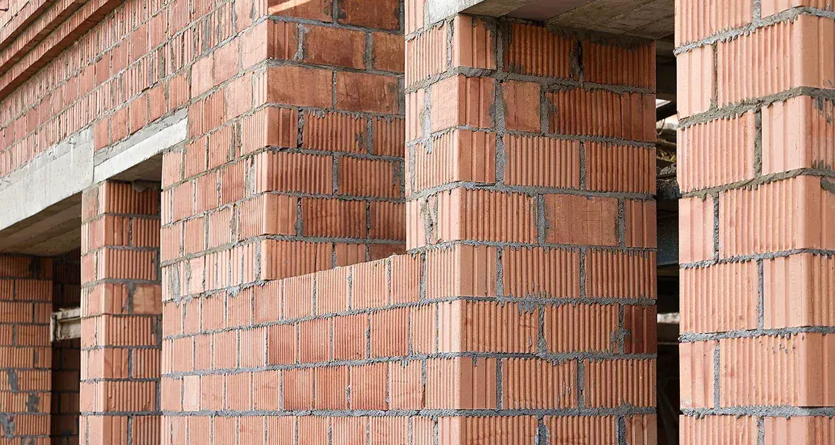 Ściany z pustaków ceramicznych w trakcie budowy. Widoczne różne rodzaje pustaków, tworzące solidną konstrukcję.