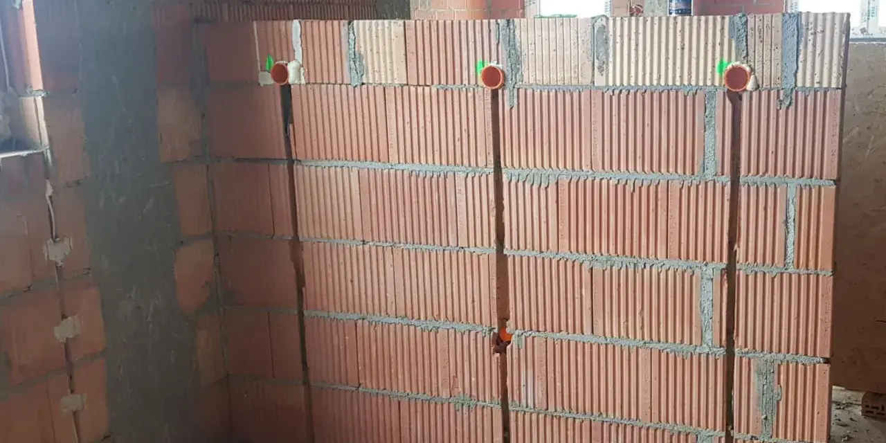 Wykonano bruzdowanie pod kable w ścianie z pustaków ceramicznych. Widoczne są puszki instalacyjne.