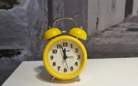 Żółty budzik z dzwonkami, który może oznaczać zakłócanie ciszy nocnej.