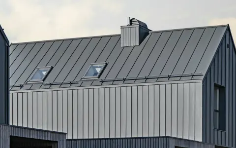 Nowoczesny dach z blachy na rąbek. Sprawdź blacha na rąbek cena m2, by poznać koszty pokrycia. Dwa okna dachowe i komin.