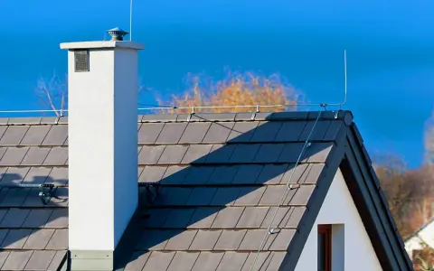 System odgromienia domu na dachu z dachówki, z kominem i piorunochronem.
