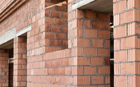 Ściany z pustaków ceramicznych w trakcie budowy. Widoczne różne rodzaje pustaków, tworzące solidną konstrukcję.