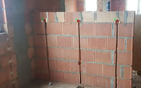 Wykonano bruzdowanie pod kable w ścianie z pustaków ceramicznych. Widoczne są puszki instalacyjne.