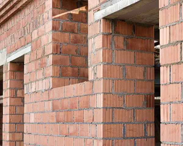 Ściany z pustaków ceramicznych w trakcie budowy. Widoczne różne rodzaje pustaków, tworzące solidną konstrukcję.
