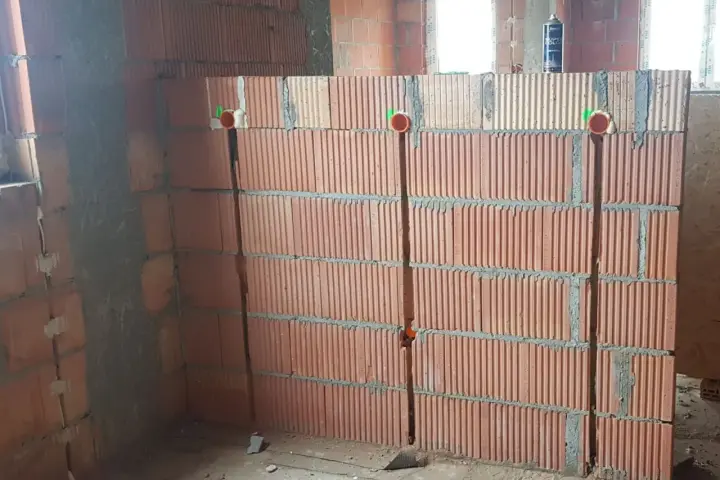 Wykonano bruzdowanie pod kable w ścianie z pustaków ceramicznych. Widoczne są puszki instalacyjne.