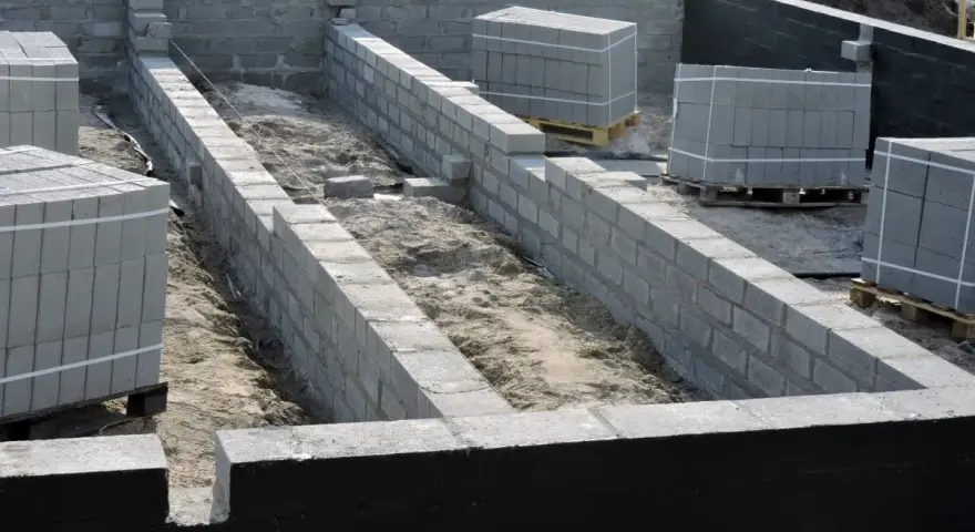 Budowa fundamentów z bloczków betonowych, przygotowanie pod izolację pionową fundamentów.