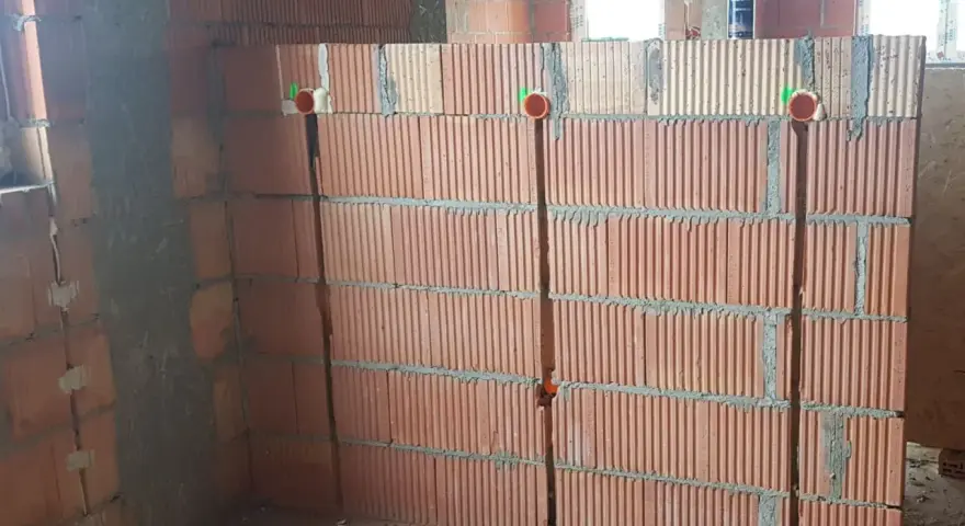 Wykonano bruzdowanie pod kable w ścianie z pustaków ceramicznych. Widoczne są puszki instalacyjne.