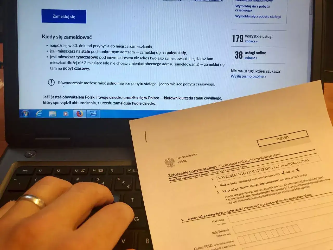 Formularz zgłoszenia pobytu stałego i instrukcja, jak się wymeldować. Dłoń na klawiaturze laptopa.